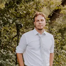 Andrew Smith outdoors, head and shoulders, with green trees behind him.